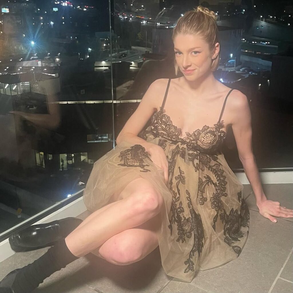 Hunter Schafer in a dress, sitting on floor